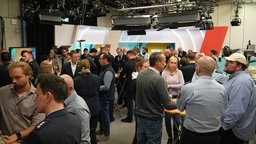 An verschiedenen Stehtischen im Fernsehstudio diskutieren Vertreter von Polizei und WDR