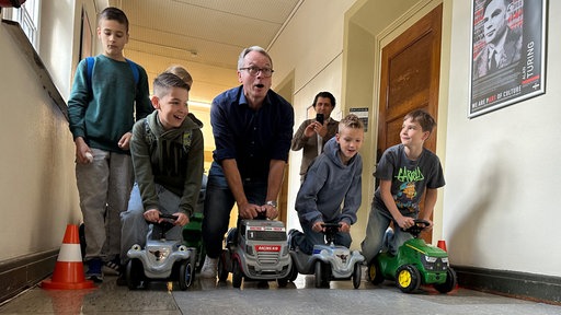 Das Bild zeigt Dattelns Bürgermeister André Dora und Schüler der Grundschule Meckinghoven auf Bobby Cars.