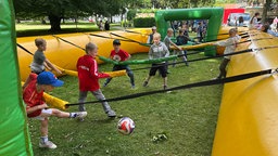 Das Bild zeigt spielende Kinder in einem lebensgroßen Kicker.