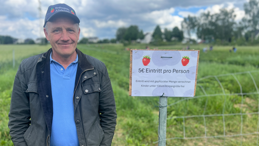 Der Landwirt Antonius Alteköster steht vor der Erdbeerplantage. Neben ihm ein Schild mit der Aufschrift "5 Euro Eintritt pro Person".