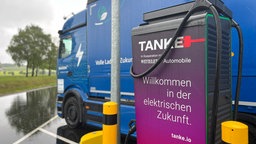 Eine Ladesäule für E-LKW. Dahintersteht ein blauer LKW.
