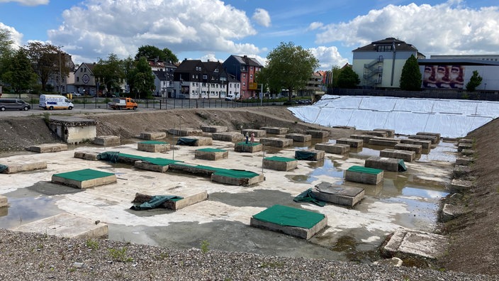 Baustelle mit vorbereiteten Fundamenten unter blauem Himmel.
