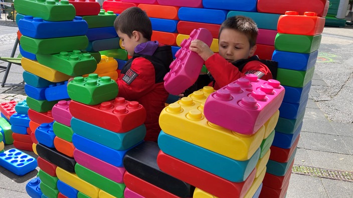 Zwei Kinder bauen mit großen bunten Bausteinen.