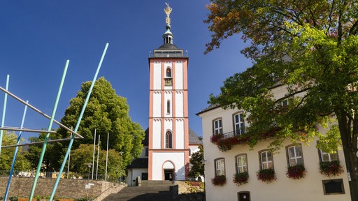 Eine Kirche mit einem sechseckigen Grundriss, steht im Mittelpunkt eines Rathausplatzes.