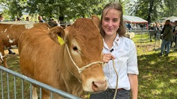 Johanna Winter steht neben ihrem braungefärbte Limousin-Rind Ute