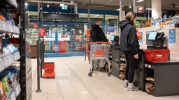 Kunden stehen an Selbstbedienungskassen und scannen ihre Waren ein