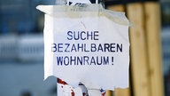 "Suche bezahlbaren Wohnraum" steht auf dem Zettel an einem Laternenmast