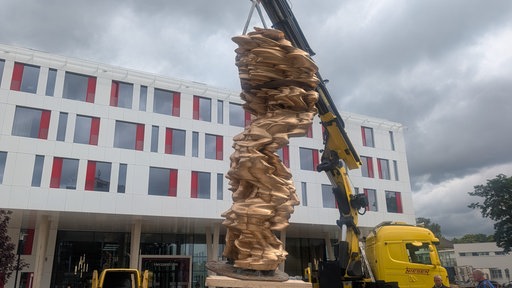 Die Skulptur "Mean Average" hängt an einem Kran