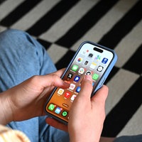 Eine Jugendliche sitzt auf dem Boden und hält ein Smartphone in der Hand