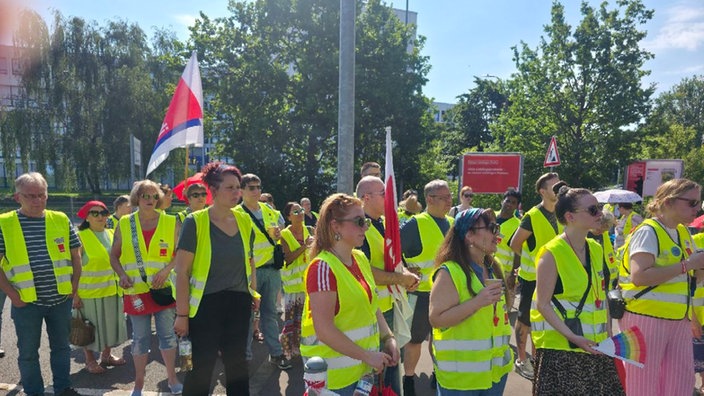 Streikende in gelben Warnwesten laufen in einem friedlichen Protest mit wehenden Verdi-Flaggen.