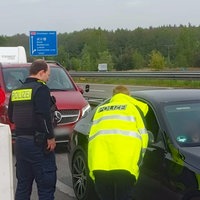 Polizisten stehen auf einer separaten Spur an der Autobahn und sprechen mit dem Fahrer eines Auto. Hinter ihm stauen sich weitere Fahrzeuge.