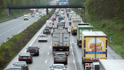 Stau auf einer mehrspurigen Autobahn mit vielen Autos und Lastwagen im dichten Verkehr.