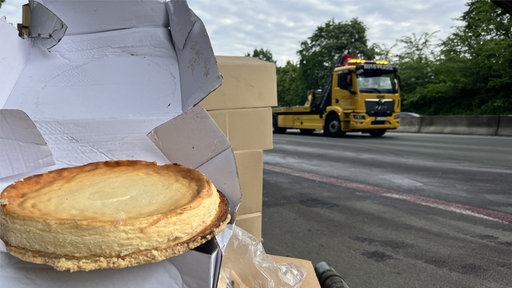 Ein Käsekuchen vor einem gelben ADAC-LKW.