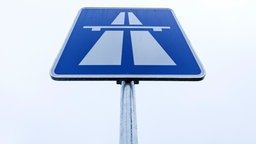 Ein rechteckickes Autobahnschild mit einem blauen Hintergrund und einem weißem Autobahnsymbol.
