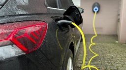 Ein E-Auto steht vor einem Privathaus und wird an einer Wallbox geladen.