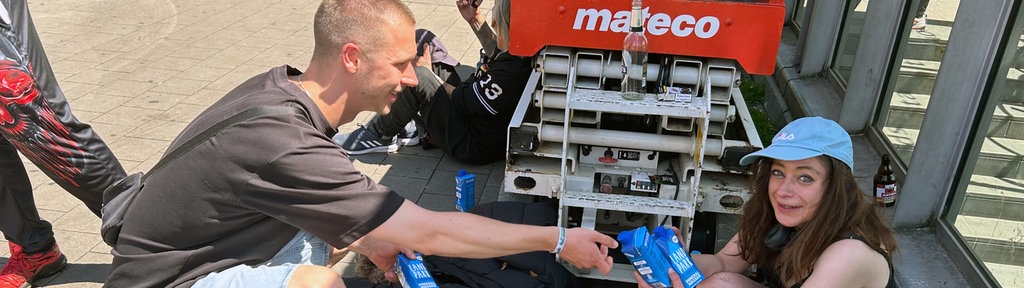 Hitzehelfer verteilt Wasser an eine lächelnde Frau.