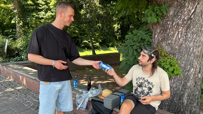 Hitzehelfer verteilt Wasser an einen Mann.