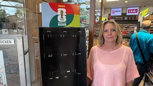 Kiosk-Verkäuferin neben einem leeren Regal für Panini-Sticker