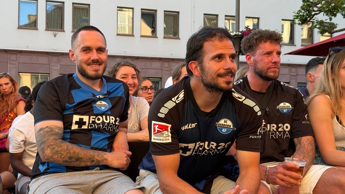 Mehrere Zuschauer verfolgen das Spiel Paderborn gegen Wolfsburg in einem Biergarten in Paderborn