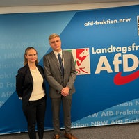 AfD-Jugendlandtags-Abgeordnete Mia und Niklas vor einer AfD-Plagaktwand im Landtag von Nordrhein-Werstfalen