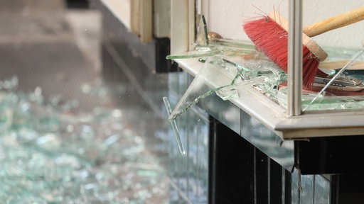 In Oberhausen räumen Menschen Glas aus ihrem durch eine Explosion beschädigtes Geschäft aus. Auch das Parteibüro der Linke war 2022 betroffen