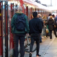 Eine rote S-Bahn steht an einem Bahnsteig. Menschen steigen ein und aus.