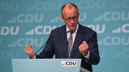 Auf der Bühne des Landesparteitags steht Friedrich Merz und redet gestikulierend