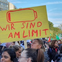 Menschen mit bunten Plakaten demonstrieren vor dem Landtag in Düsseldorf, auf einem steht unter einem Batteriesymbol: "Wir sind am Limit".