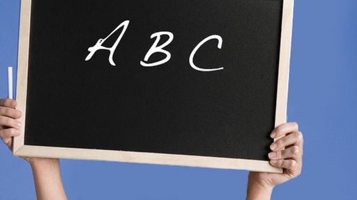 Eine Frau hält eine Tafel mit der Aufschrift "ABC" hoch