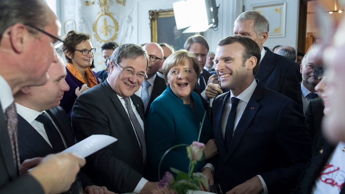 Damalige Ministerpräsident Armin Laschet, Kanzlerin Angela Merkel (beide CDU) und Frankreichs Präsident Emmanuel Macron lachen im Jahr 2019 bei Unterzeichnung des Aachener Vertrages