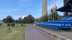 Tribüne vor NRW Landtag mit blauen Sitzen, im Hintergrund der Fernsehturm, Auf der Wiesen sind Lautsprecher aufgebaut und Rekruten laufen in Uniform über die Wiese