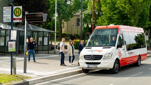 Ein Kleinbus hält an einer Bushaltestelle