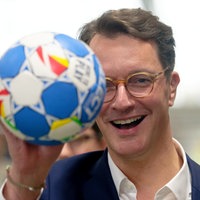 Hendrik Wüst (CDU) hält einen Handball in die Kamera