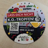 Ein bunt bedruckter Bierdeckel liegt auf einem Tisch, auf ihm steht "Jeck aber sicher", dazu Infos zum Verhalten für Opfer von K.O.-Tropfen