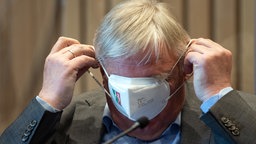 NRW-Gesundheitsminister Karl-Josef Laumann (CDU) setzt sich eine Maske auf, Aufnahme vom 04.02.2021