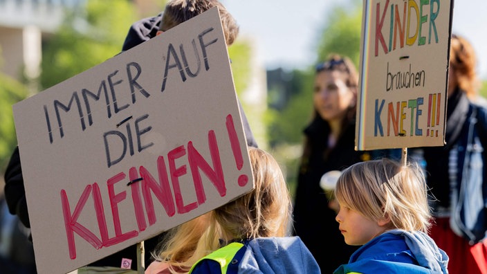 Zwei Kinder sind vor dem NRW-Landtagsgebäude teil einer Demonstration und halten Schilder hoch.
