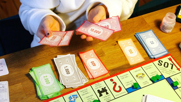 Kinderhände mit Spielgeld bei einer Partie Monopoly