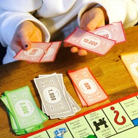 Kinderhände mit Spielgeld bei einer Partie Monopoly