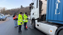 Ein LKW wird vor der Wiehltalbrücke von zwei Männern in gelben Jacken kontrolliert.