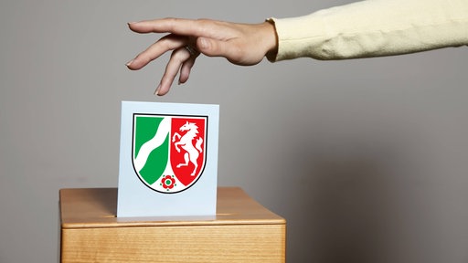 Wahlzettel wird in eine Wahlurne geworfen