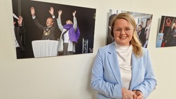 Lisa Kapteinat (SPD) steht vor einem Foto, das die frühere Ministerpräsidentin Hannelore Kraft mit einem Schal im Gesicht zeigt