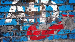 Eine Mauer mit einem von der Wand bröckelnden Aufputz des AfD-Logos