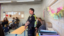 Ein Polizist steht in einer Schulklasse