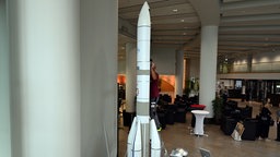 Ein Techniker arbeitet an einer vier Meter hohen Nachbildung einer Ariane-6-Rakete im Landtag NRW