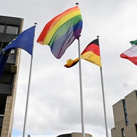 Vor dem Landtag in Düsseldorf weht eine Regenbogenflagge neben einer Deutschlandflagge, einer Europaflagge und einer Flagge mit dem NRW-Landeswappen.