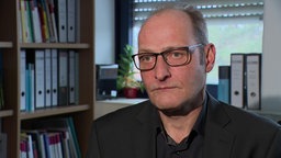 Experte Marcus Kober vom Stiftung Deutsches Forum für Kriminalprävention, im Hintergrund Aktenordner 