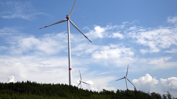 ARCHIV - 06.06.2023, Nordrhein-Westfalen, Bad Berleburg: Wolken ziehen über Windräder zur Stromerzeugung. In Nordrhein-Westfalen wird es für sechs Monate ein Genehmigungsmoratorium für Windkraftanlagen außerhalb bestimmter Planungszonen geben.