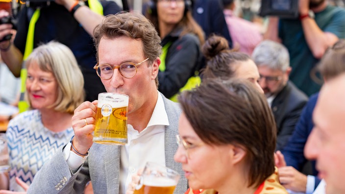 Ministerpräsident Hendrik Wüst (CDU) trinkt ein Bier auf der Cranger Kirmes