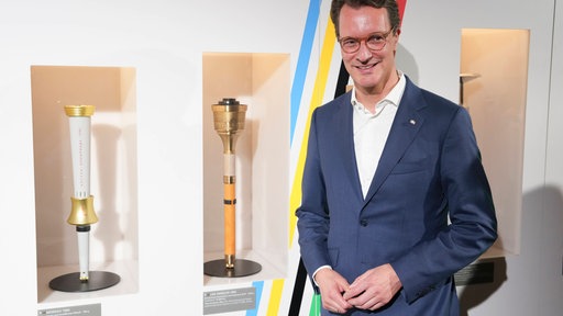 NRW-Ministerpräsident Hendrik Wüst (CDU) neben olympischen Fackeln im Deutschen Sport und Olympia-Muesum in Köln