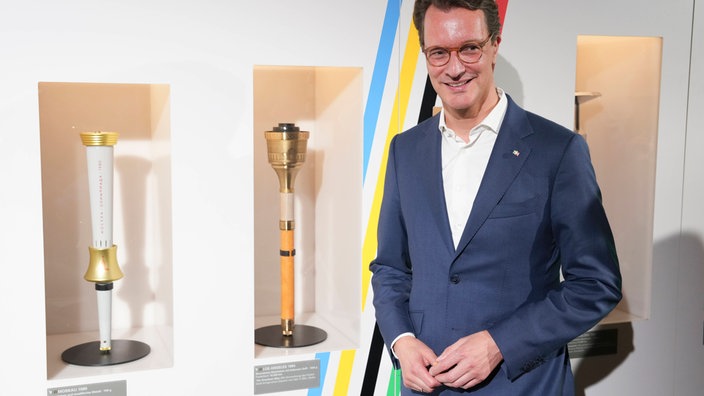 NRW-Ministerpräsident Hendrik Wüst (CDU) neben olympischen Fackeln im Deutschen Sport und Olympia-Muesum in Köln